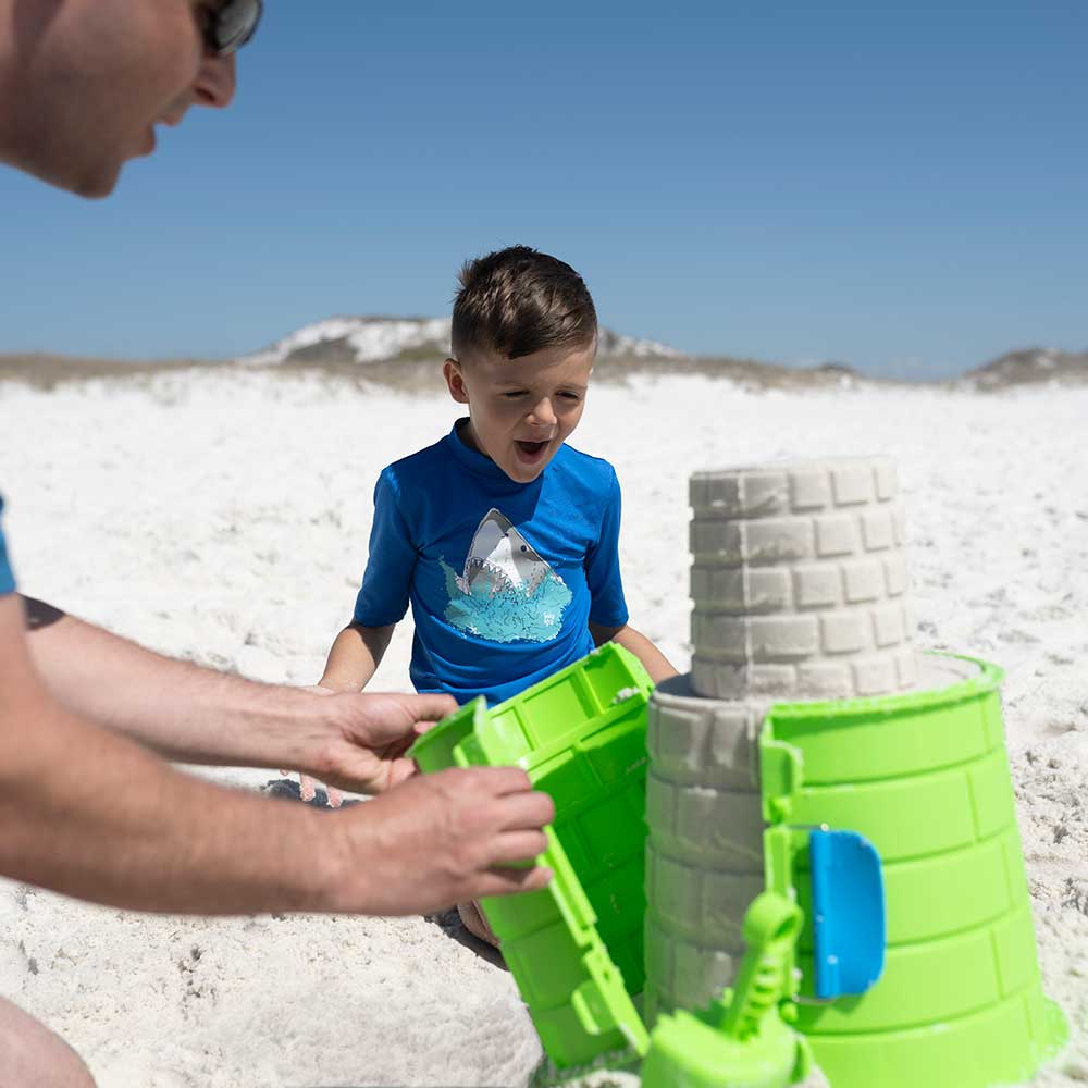 Father and son using Create A Castle sandcastles with on a soft sandy beach